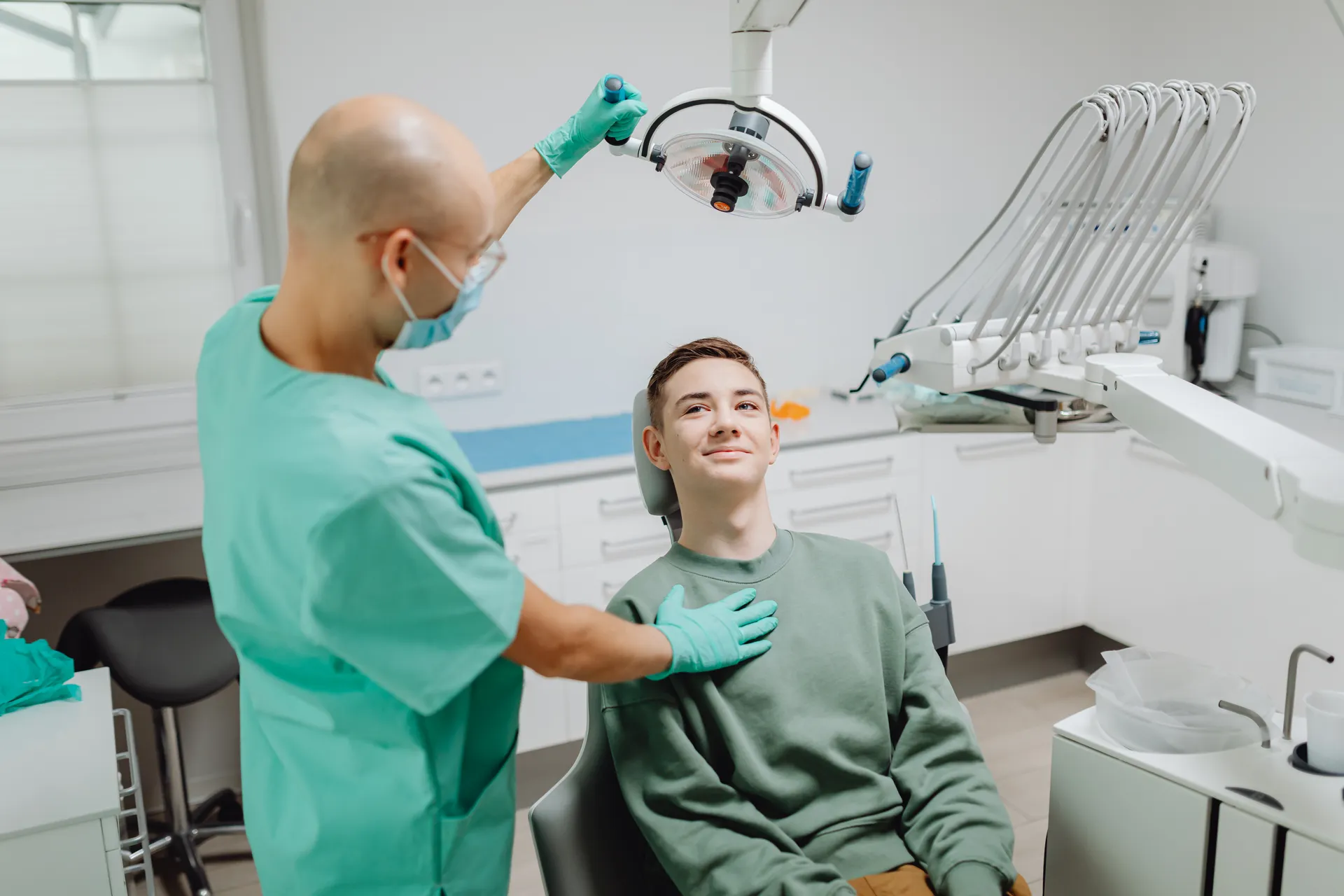Dentist welcoming a smiling patient into the treatment chair