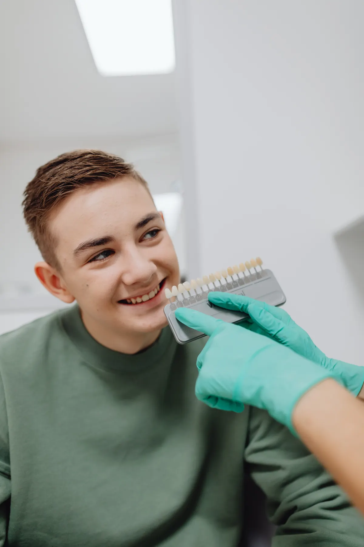 Dentist comparing a shade guide with a smiling young patient